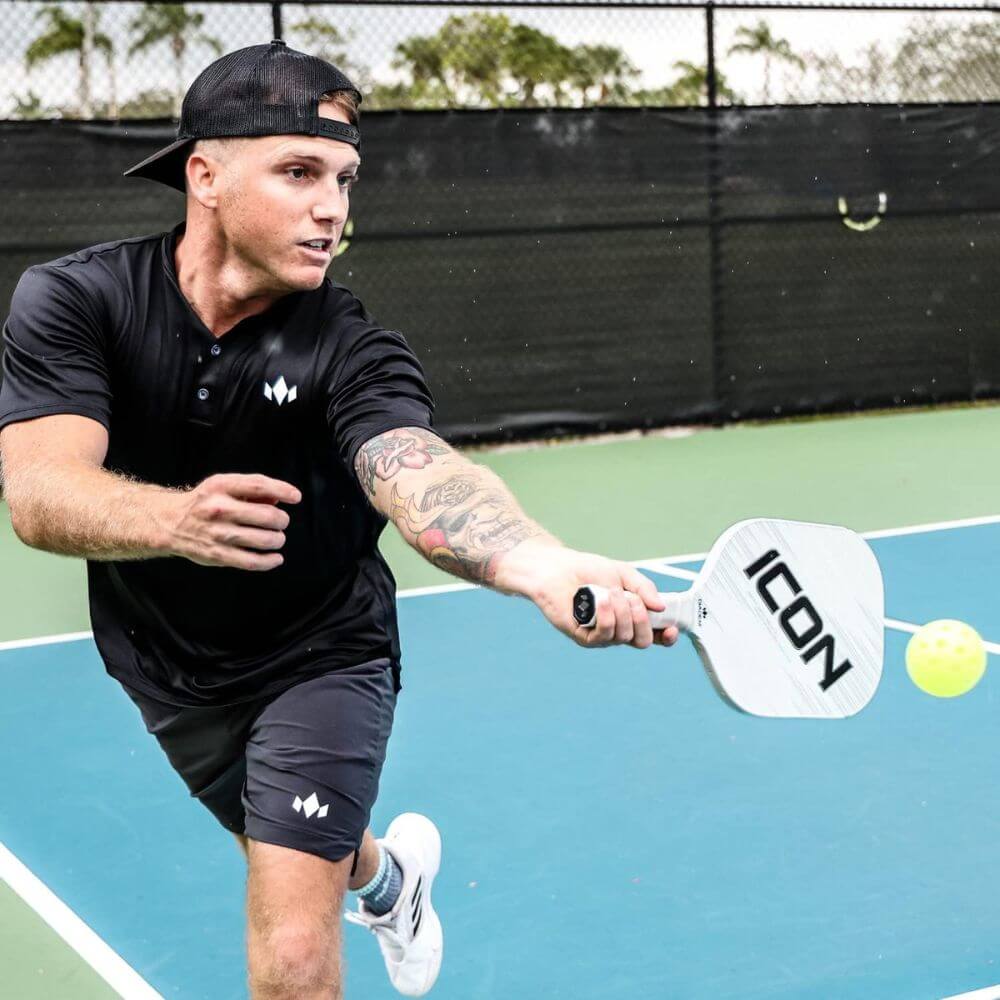 man playing pickleball with white icon paddle 