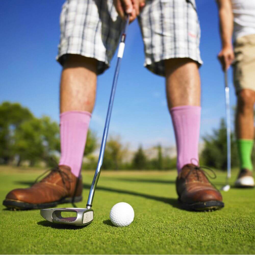 man on putting green with purple socks and brown golf shoes