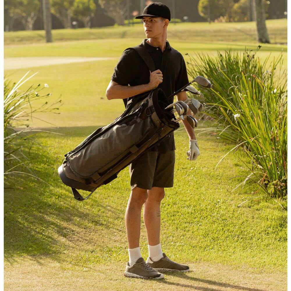 man with all black attire with golf bag on his shoulder
