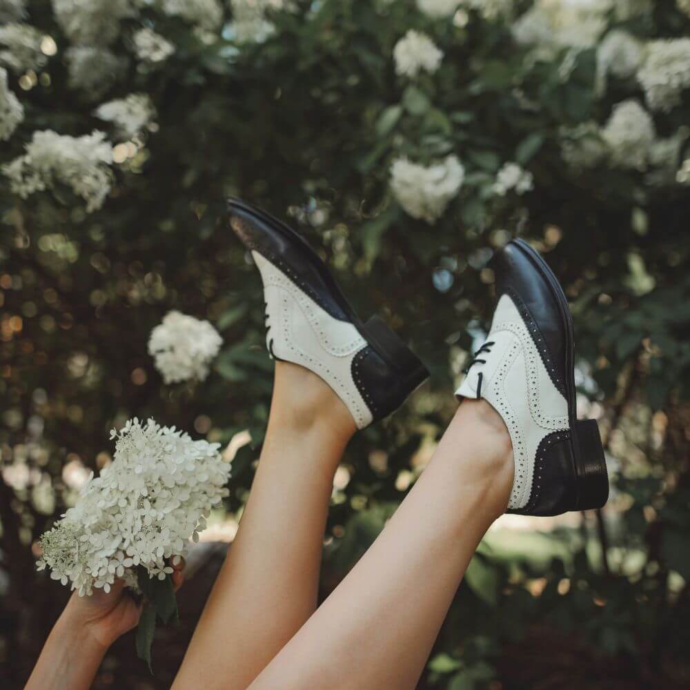 woman upside down with white flowers and black and white golf shoes
